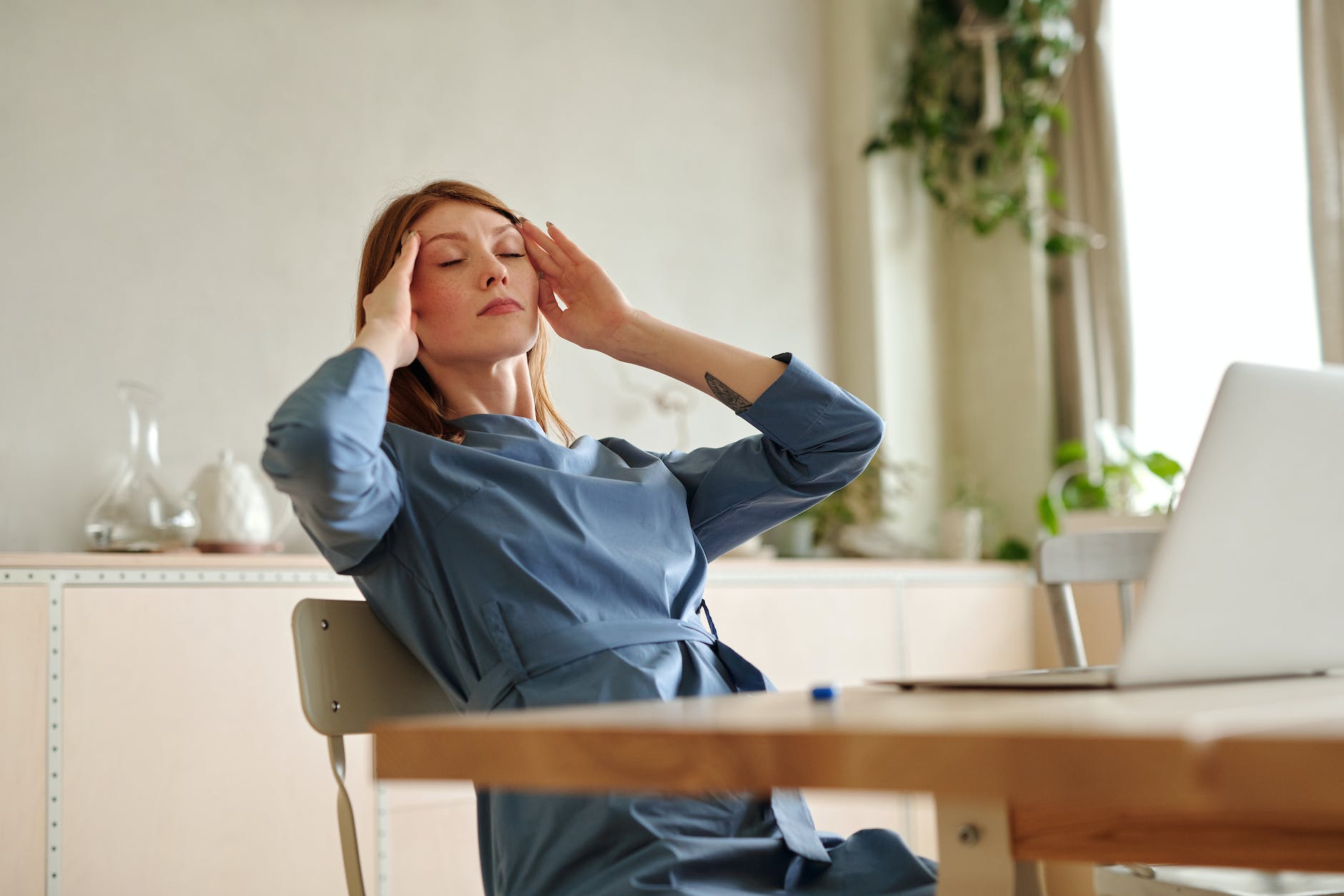 woman in blue dress touching her head